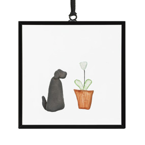 A small square suncatcher with a dog next to a plant made out of small colored stones.