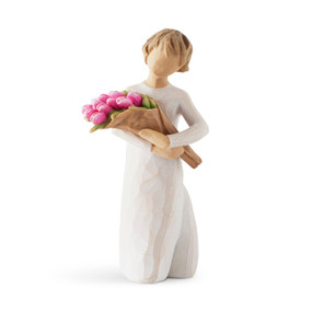 Front view of standing figure in cream dress holding bouquet of pink tulips