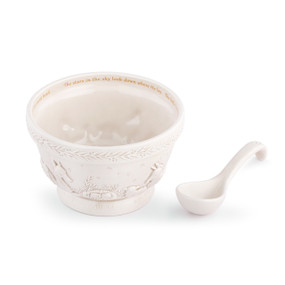 A cream ceramic serving bowl and spoon with raised images on the outside of the nativity scene. The inner rim of the bowl has the lyrics of Away in a Manger in gold.