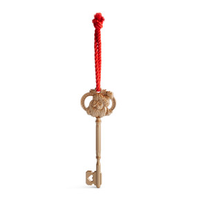 A dull metal key with the face of Santa hanging from a red rope hanger.