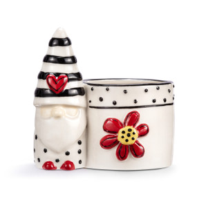 A mini white ceramic planter with a black and white gnome figure attached to the side. The planter has black dots and a raised red flower on the front.