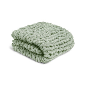 A light green chunky knit blanket displayed folded.