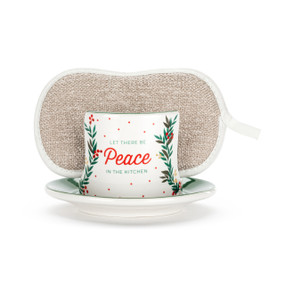 A white ceramic soap dish with the saying "Let There Be Peace In The Kitchen" and a floral illustration, with a tan sponge in the open slot.