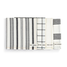 A set of four cream cloth napkins each with a different pattern of gray stripes or plaid. Each has a small fabric tag with a different fun saying at the bottom corner.