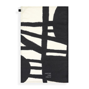 A tea towel with artwork inspired by ArtLifting artist Linda King of a black and white geometric pattern that says "Inspire Cook Create" at the bottom.