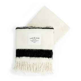 A cream and black fringed blanket with a fabric patch that reads "i can & will Slip On Stretchy Pants And Call It A Day".