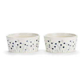 Two white ceramic ramekins with a small blue flower pattern on the outside, displayed at an angle to show the lip on the inside rim allowing them to stack.