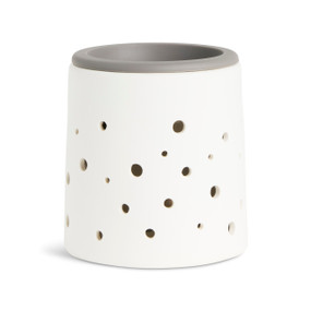 A white wax melter with holes in the side and a gray silicone dish in the top.