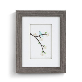 A gray wood framed image of a light blue bird perched on a flowering tree branch made of pebbles.