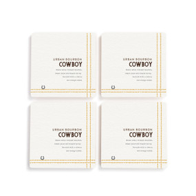 A set of four white square coasters with a basic recipe for an Urban Bourbon Cowboy written in black.