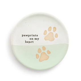 A small round light green and white ceramic trinket dish with two tan paw prints and the saying "pawprints on my heart".