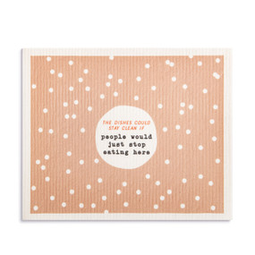 An oversized peach and white polka dot biodegradable dish cloth with the saying "The Dishes Could Stay Clean If people would just stop eating here".