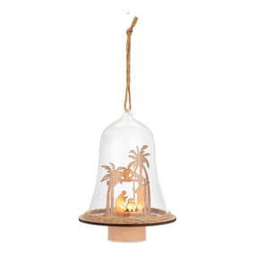 A lit cloche ornament with a nativity scene cutout inside.