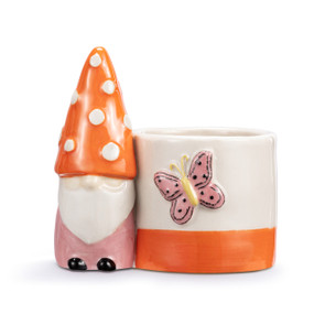 A mini white ceramic planter with a pink and orange gnome figure attached to the side. The planter has an orange stripe at the bottom and a raised pink butterfly on the front.