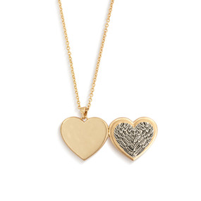 A gold chain necklace with a heart shaped locket charm. The front of the locket is molded in a silver feather pattern to look like wings.