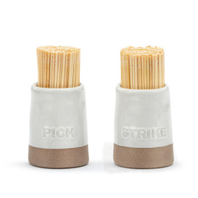 A set of two cream ceramic toothpick and match holders with a brown textured base. One says "Pick" and the other says "Strike", displayed with toothpicks inside.