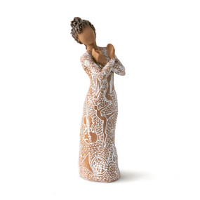 Front view: Darker-skin figure carved with contrasting pattern of white musical symbols, instruments, dancing forms