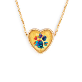Detail view of the charm on an adjustable gold chain necklace with a heart shaped charm of a colorful paw print.