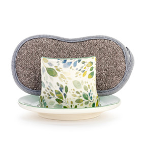 A cream ceramic soap dish with green and blue spring leaves, and a gray sponge in the open slot.