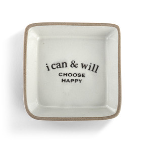 A square cream ceramic trinket dish with a tan textured rim that says "i can & will Choose Happy" on the inside.