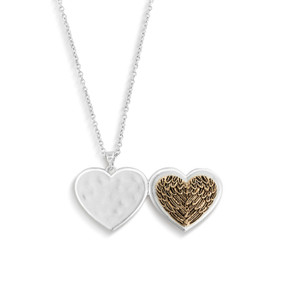 A silver chain necklace with a heart shaped locket charm. The front of the locket is molded in a gold feather pattern to look like wings.