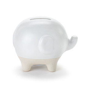 A white ceramic piggy bank with the face and trunk of an elephant. The feet of the bank are cream and textured.