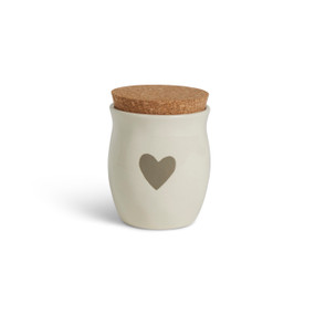 A cream ceramic candle with a gray heart. The candle has a cork lid.