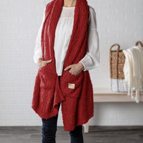 A woman in a white blouse, dark denim jeans and a red "Giving Shawl".