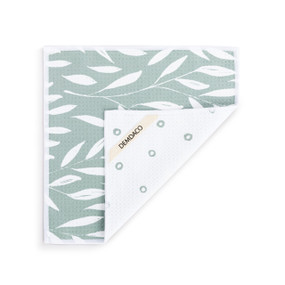 A double sided square dish cloth that is light green on one side with white leaf illustrations, displayed with the corner turned back.