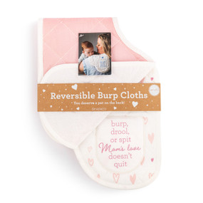 A set of two burp cloths in pink and white. One is pink and the other has a pink heart pattern and says "burp, drool, or spit Mom's love doesn't quit", displayed in a packaging band.