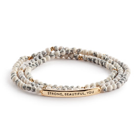 A multi-strand beaded bracelet in a mix of white with a gold metal bar that says "Strong, Beautiful, You".