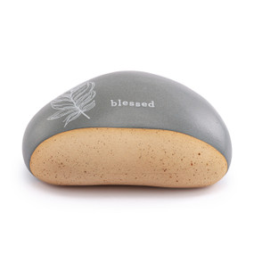 A gray and tan stoneware rock with a feather illustration in white with the word "blessed" on the top.