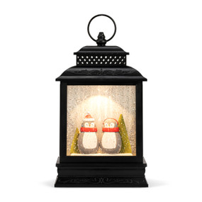 A black lit musical lantern with an image of two penguins in the snow.