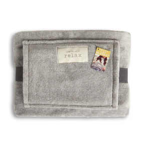 A light gray lap blanket with a hand pocket. The fabric patch says "relax and press pause", wrapped in a gray ribbon with a product tag attached.