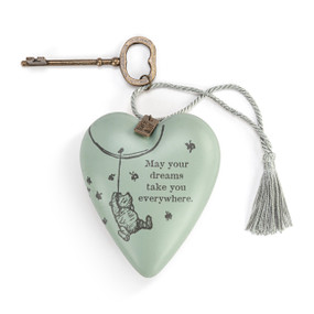 Heart shaped sculpture with a silver tassel and metal key attached. The heart has the image of Pooh hanging from a balloon on a light green background and says "May your dreams take you everywhere".
