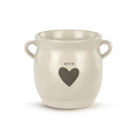 A cream ceramic planter with two small handles on the sides. The planter says "mom" and has a gray heart on the front.