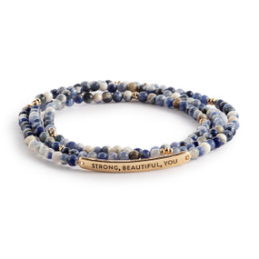 A multi-strand beaded bracelet in a mix of blue and white with a gold metal bar that says "Strong, Beautiful, You".