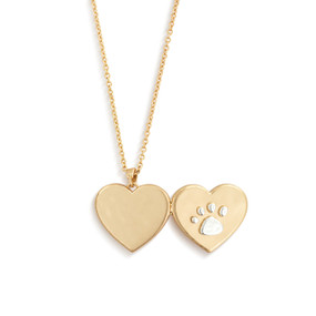 A gold chain necklace with a heart shaped locket charm. The front of the locket has a silver paw print on it.