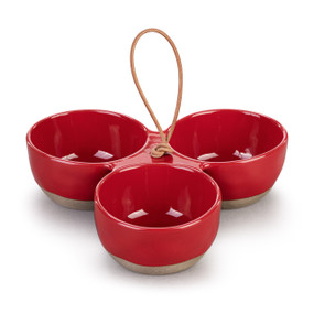 A red ceramic tri-bowl with a cord handle in the middle and tan textured bases on the bowls.