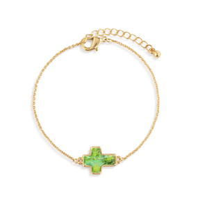 A gold chain adjustable bracelet with a cross shaped charm illustrated with green and has the word "Faith" on the back.