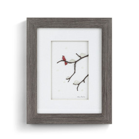 A gray wood framed image of a red bird on snowy tree branches made of pebbles.