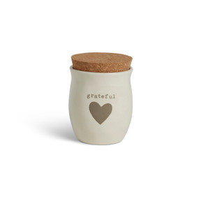 A cream ceramic candle with a gray heart and the word "grateful". The candle has a cork lid.