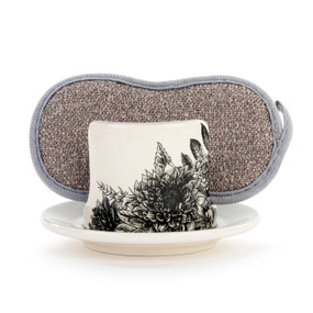 A cream ceramic soap dish with a black line drawn floral pattern, and a gray sponge in the open slot.