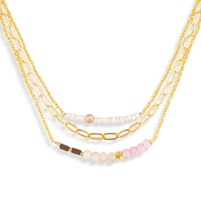 A layered gold necklace made of three different chains with light colored beads on them.