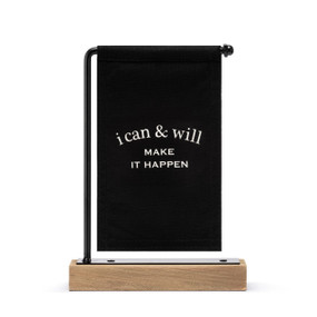 A black canvas sign with white writing that says "i can & will Make It Happen" hanging on a black metal stand with a wood base.