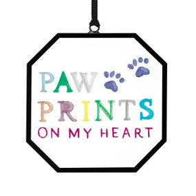 A small octagon shaped sun catcher with blue paw prints and the saying "Paw Prints On My Heart" in different colors.