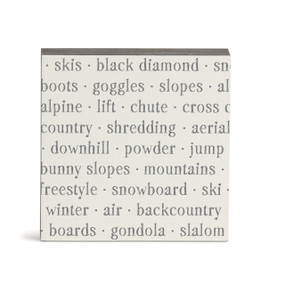 A white square wall art with words about skiing on it.