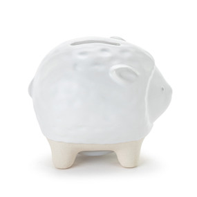 A white ceramic piggy bank with the face and ears of a lamb. The feet of the bank are cream and textured.