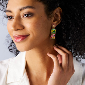 A woman wearing a pair of earrings with an image of a poppy field on them.