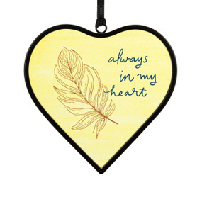 A small yellow heart shaped sun catcher with a feather illustration and the saying "always in my heart".
